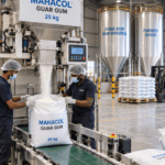 Exploring the Global Impact of Guar Gum: Production and Distribution Industrial facility showing workers filling 25 kg bags during guar gum production with a Mahacol guar gum packaging bags and machine.