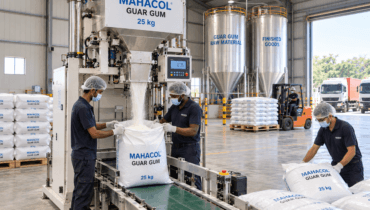 Industrial facility showing workers filling 25 kg bags during guar gum production with a Mahacol guar gum packaging bags and machine.
